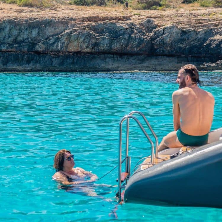Couple enjoying a refreshing swim in the turquoise waters of a hidden cove in Mallorca, accessible from an Attraction Catamarans catamaran.
