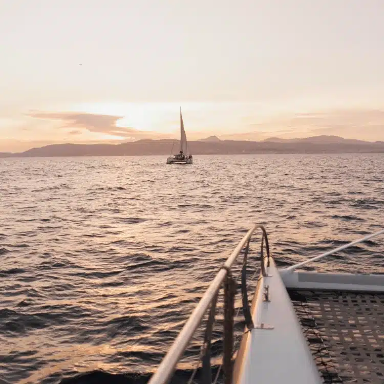 Atardecer en un catamarán de lujo en Mallorca. Vista de la proa con otra embarcación navegando al fondo. 