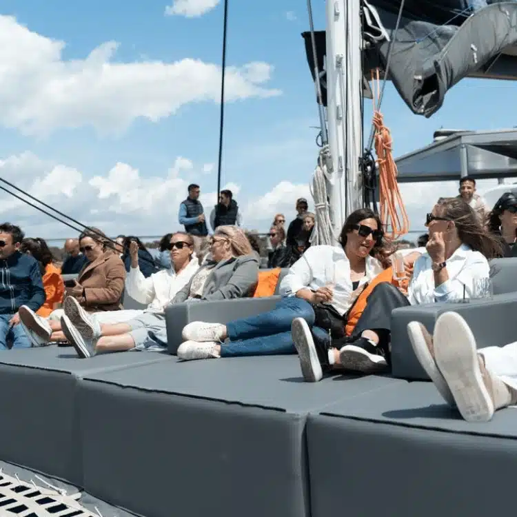 Grupo de personas relajadas en las colchonetas de la cubierta de uno de los catamaranes de Attraction.
