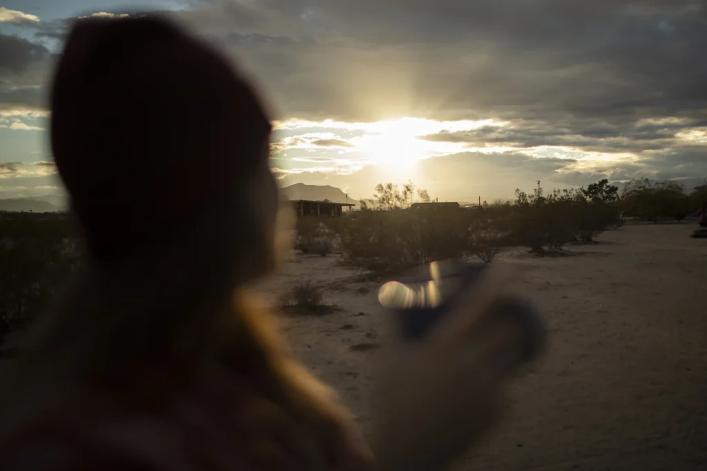 Persona observando un atardecer en un paisaje desértico, preparándose para fotografiar. Representa la expectativa y la búsqueda de ubicaciones únicas para ver el eclipse solar en Mallorca 2026.