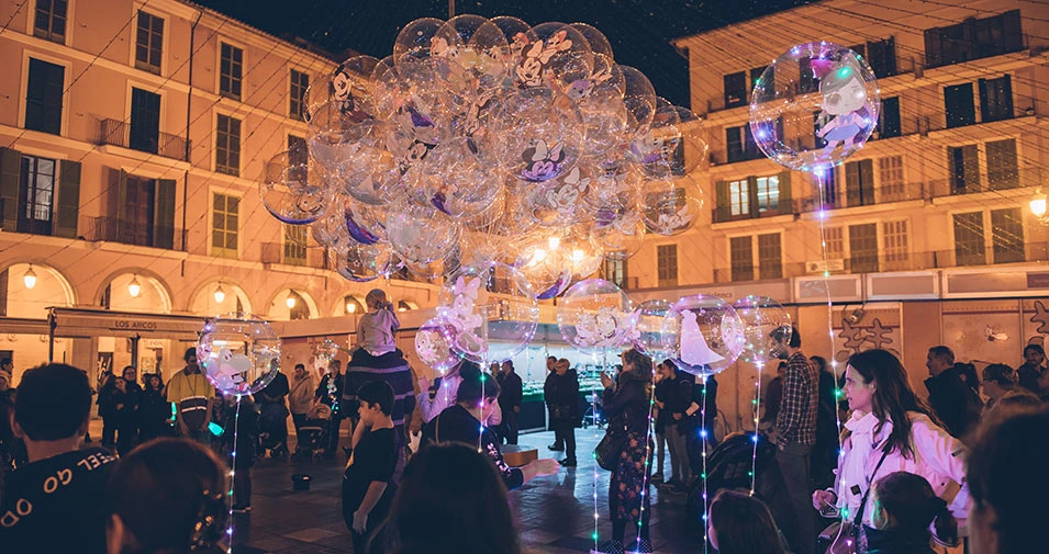 Noche de diciembre en Palma de Mallorca con luces y globos luminosos en una plaza, parte del ambiente navideño de Mallorca en el Puente de Diciembre.