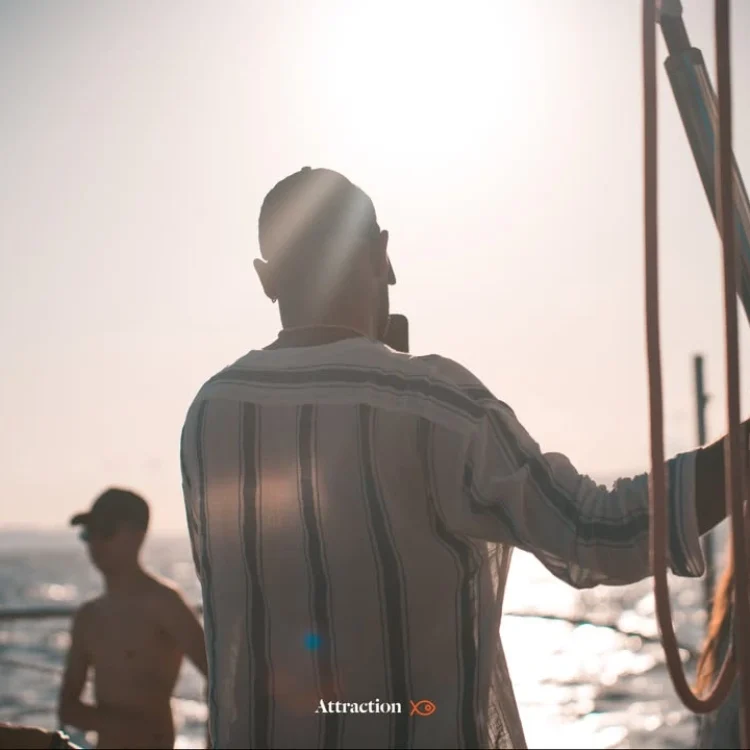 Pasajero a bordo de un catamarán de Attraction Catamarans, observando el horizonte con el sol brillante. Destaca la experiencia premium desde el mar para disfrutar del eclipse solar en Mallorca 2026.